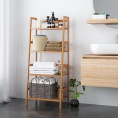 a wooden shelf with towels and baskets on it next to a sink in a bathroom