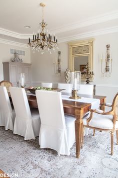 a dining room table with white chairs and a christmas tree in the background