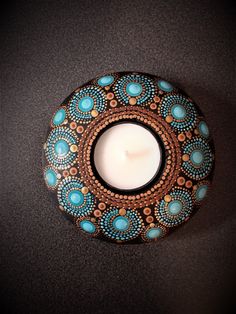 a lit candle sitting on top of a black table next to a brown and blue plate