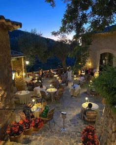 an outdoor dining area with tables, chairs and lights on the outside patio at night