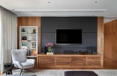 a modern living room with wood paneling and gray furniture, along with a flat screen tv mounted on the wall