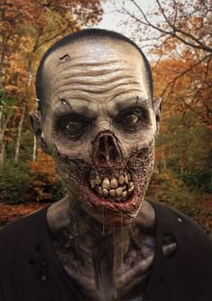 a creepy looking man with blood dripping from his mouth and nose, in the woods