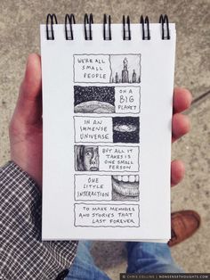 a person holding up a notebook with drawings on it