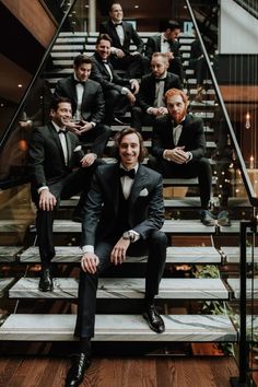 a group of men in tuxedos sitting on stairs