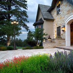 a house that has some flowers in front of it and lights on the side of the house