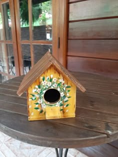 a yellow birdhouse sitting on top of a wooden table