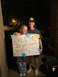 two people standing next to each other holding a sign that says call me if you want to go