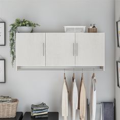 an organized closet with white cabinets and hanging clothes