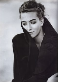 a black and white photo of a woman with her hair in a bun wearing a jacket