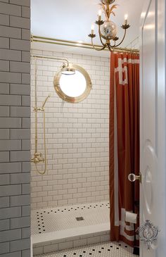 a bathroom with white tile and red shower curtain, chandelier over the bathtub