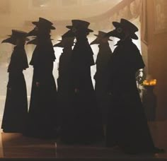 the silhouettes of five women in long black dresses and hats are shown behind a glass window