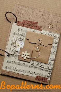 an altered album with music notes and paper flowers on it, sitting on top of a piece of cardboard