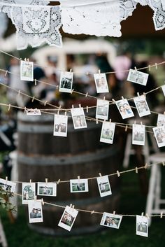 an old barrel with pictures hanging from it and clothes pins attached to the rope that hold photos