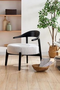 a white chair sitting on top of a wooden floor next to a potted plant