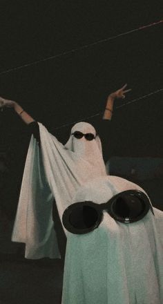 a person dressed up as a ghost with sunglasses and a white sheet draped over their head