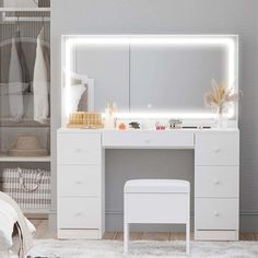 a white dressing table with a mirror and stool in a small room next to a bed