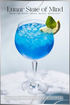 a blue drink in a glass with lime garnish