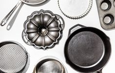 several different types of cooking utensils and pans on a white table top