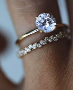 a woman's hand with two gold rings and a diamond ring on her finger