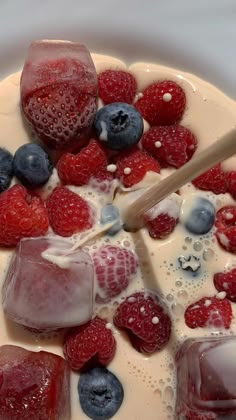 berries, blueberries and raspberries are mixed together in a cream sauce on top of ice cubes