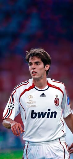 the soccer player is wearing white and red uniform with his hand on his hip as he looks down