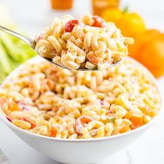 a white bowl filled with macaroni salad next to oranges and celery