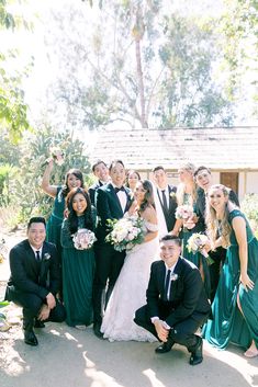 a group of people in formal wear posing for a photo together with trees and bushes behind them