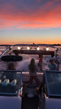 people are riding in the back of a boat at sunset