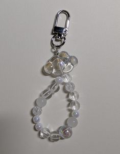 a keychain made out of glass beads and silver metal hooks on a white surface