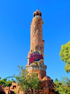 the sign for disneyland's adventure park is displayed on top of a brick tower