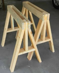 three wooden stools sitting next to each other on the floor in front of a car