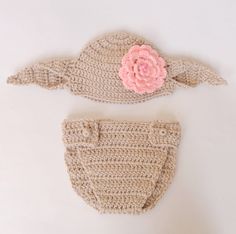 two crocheted hats and diaper covers on a white surface with a pink flower