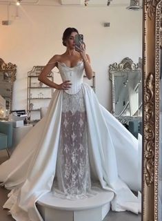 a woman taking a selfie in front of a mirror wearing a white wedding dress