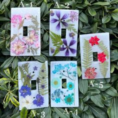 four light switch covers with flowers painted on them and leaves in the bottom right hand corner