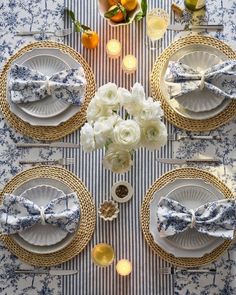 the table is set with blue and white plates, napkins, silverware, and flowers