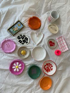 many different bowls and plates are arranged on a white sheet in the shape of a heart