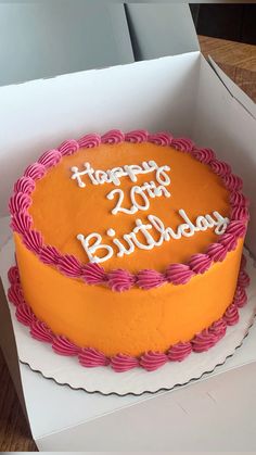 an orange and pink birthday cake in a box