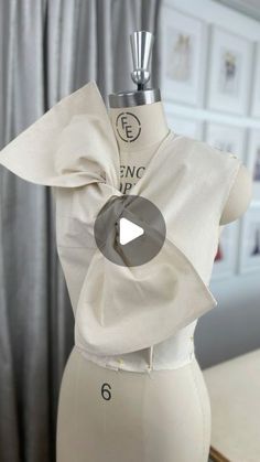 a mannequin wearing a white top with a bow on it