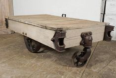 an old wooden cart sitting on top of a floor next to a white wall and door