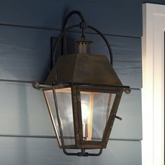 an old fashioned lantern hanging on the side of a house with blue siding and white trim