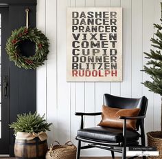 a black chair sitting in front of a christmas wreath on the wall next to a door