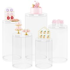 three clear plastic containers with pink decorations on top and one white container filled with cupcakes