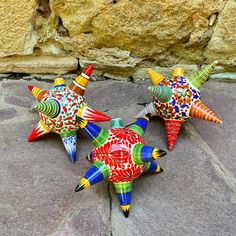 three colorful ceramic stars sitting on top of a rock