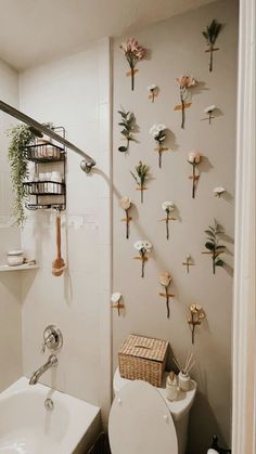 a white toilet sitting next to a bathroom sink under a wall hanging with flowers on it