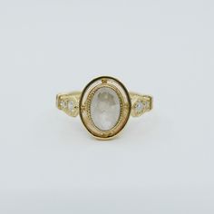 a gold ring with a white stone in the center and two small diamonds around it