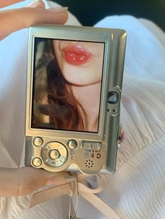 a woman holding up a small silver camera with a picture on it's screen