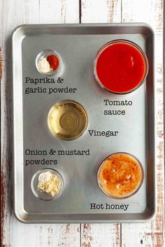 the ingredients for this recipe are in separate bowls on a metal tray, including tomato sauce, onion & mustard powder and hot honey