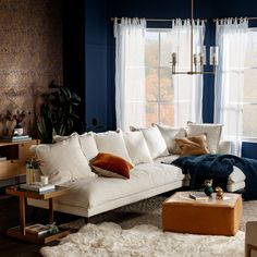 a living room with blue walls and white furniture in the corner, including a large sectional couch