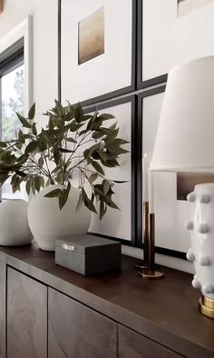 there is a vase with some plants on top of the dresser in this living room