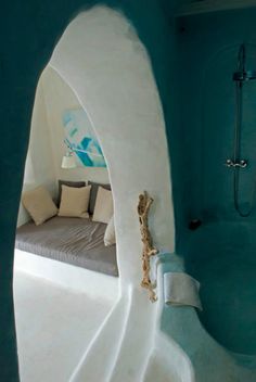 the interior of a bathroom with blue walls and flooring is decorated in white plaster